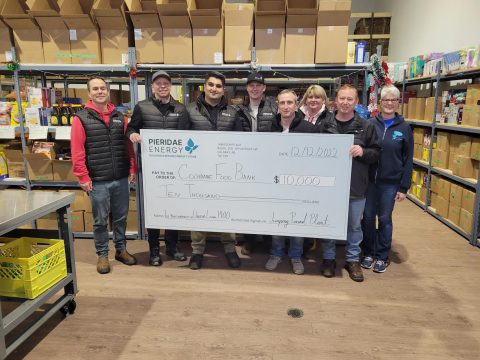 Pieridae employees standing with a member of the Cochrane Activettes in the food bank, holding a giant a cheque from Pieridae